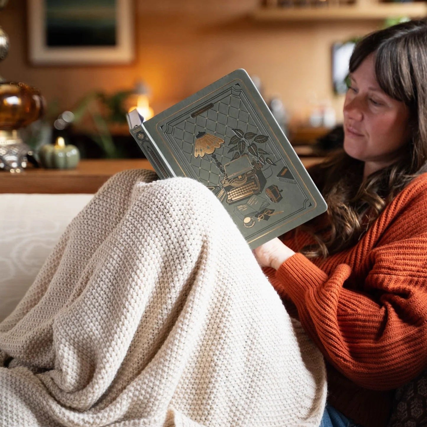 The Writer’s Desk Notebook held in a cozy reading setting
